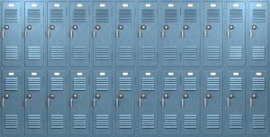 A front on view of a stack of blue metal school lockers with combination locks and doors shut on an isolated background